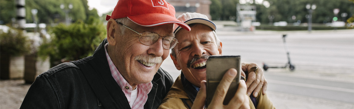 twee oudere mannen maken lachend een selfie