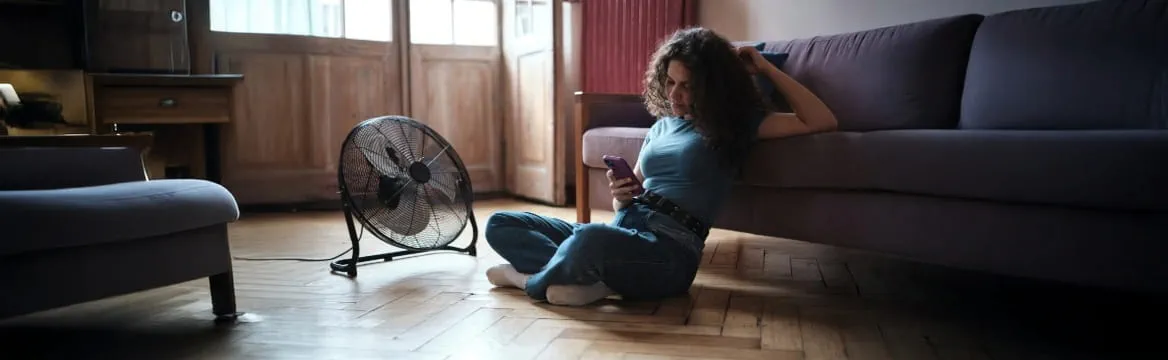 vrouw zit op de grond voor de bank met ventilator