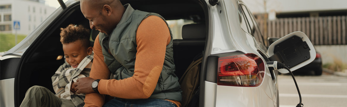 man zit met kind achterin auto met de auto aan de oplader