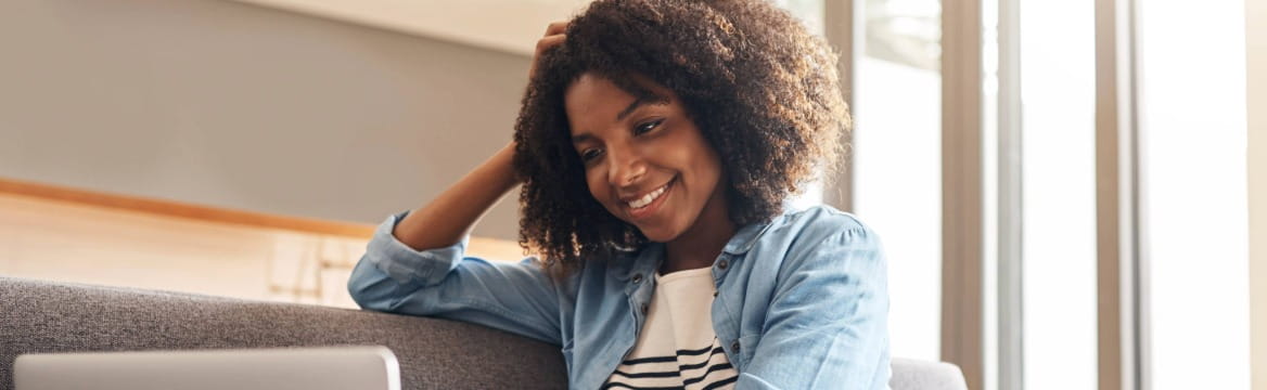 vrouw zit op de bank achter haar laptop