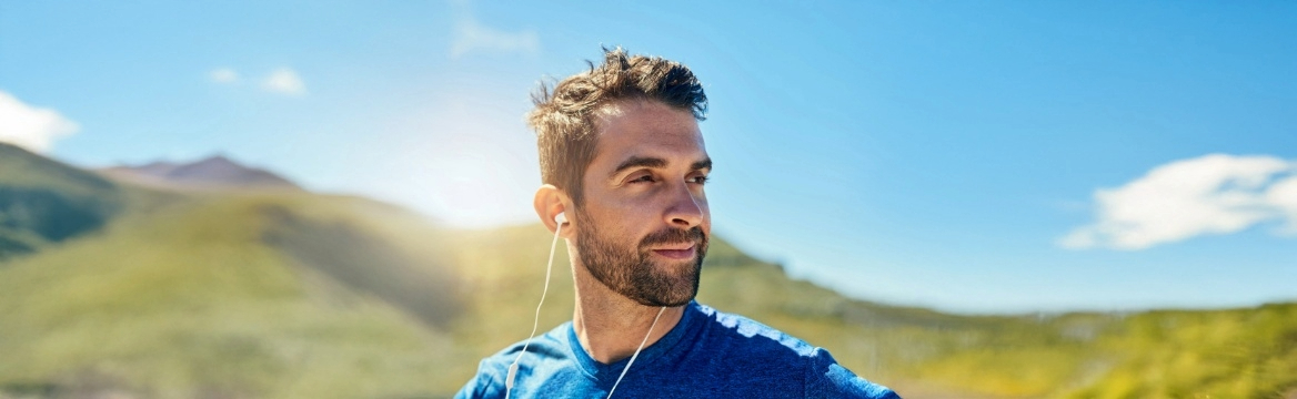 man buiten met oordopjes in en sportkleding aan