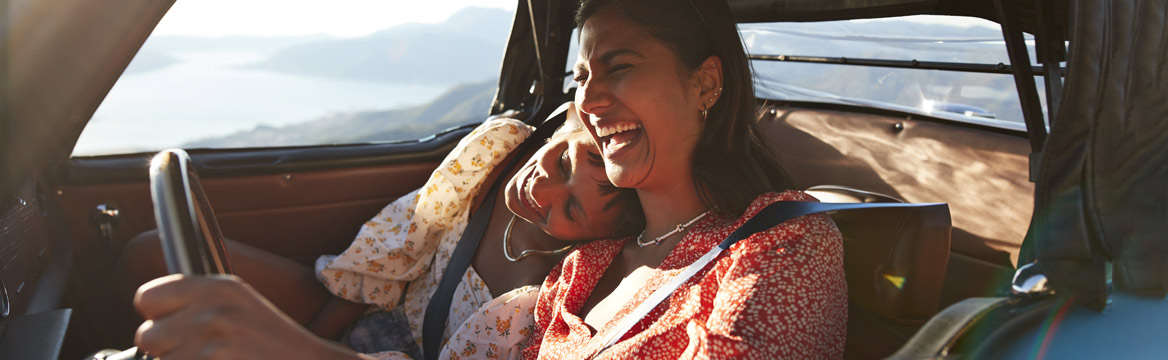 twee vrouwen lachend achter het stuur