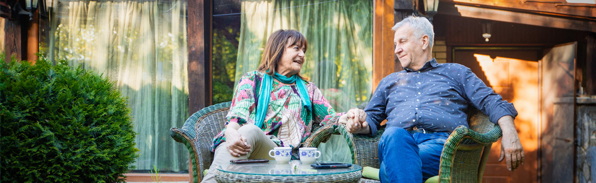 oudere man en vrouw zitten buiten in hun tuin